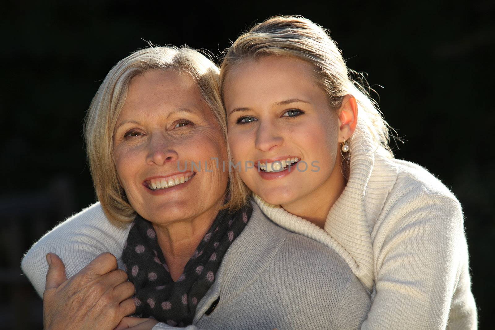 Young woman hugging her grandmother by phovoir