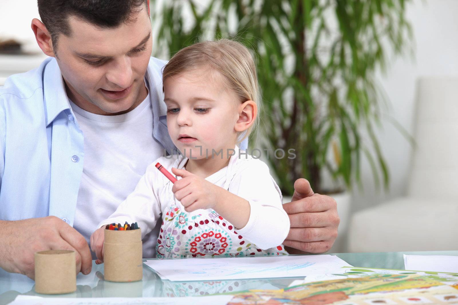 Father and daughter colouring with crayons