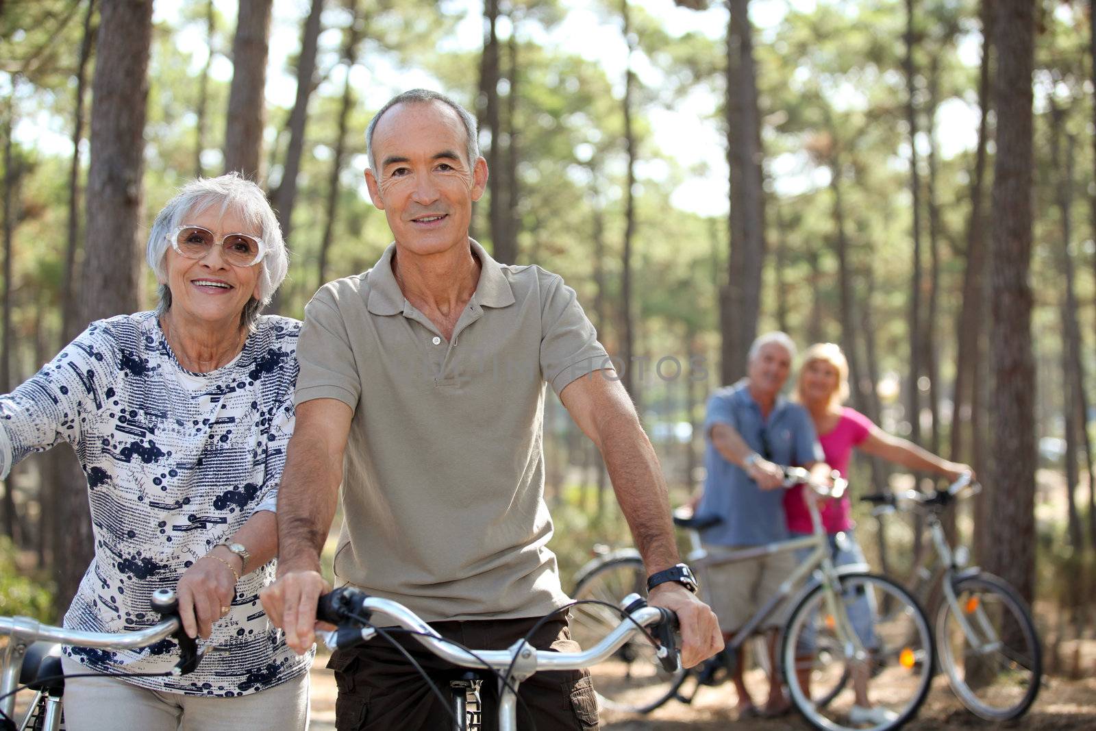 four senior people doing bike in a pine forest by phovoir