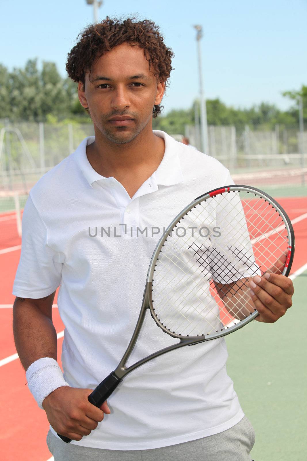 A tennis player holding his racket and looking at us. by phovoir