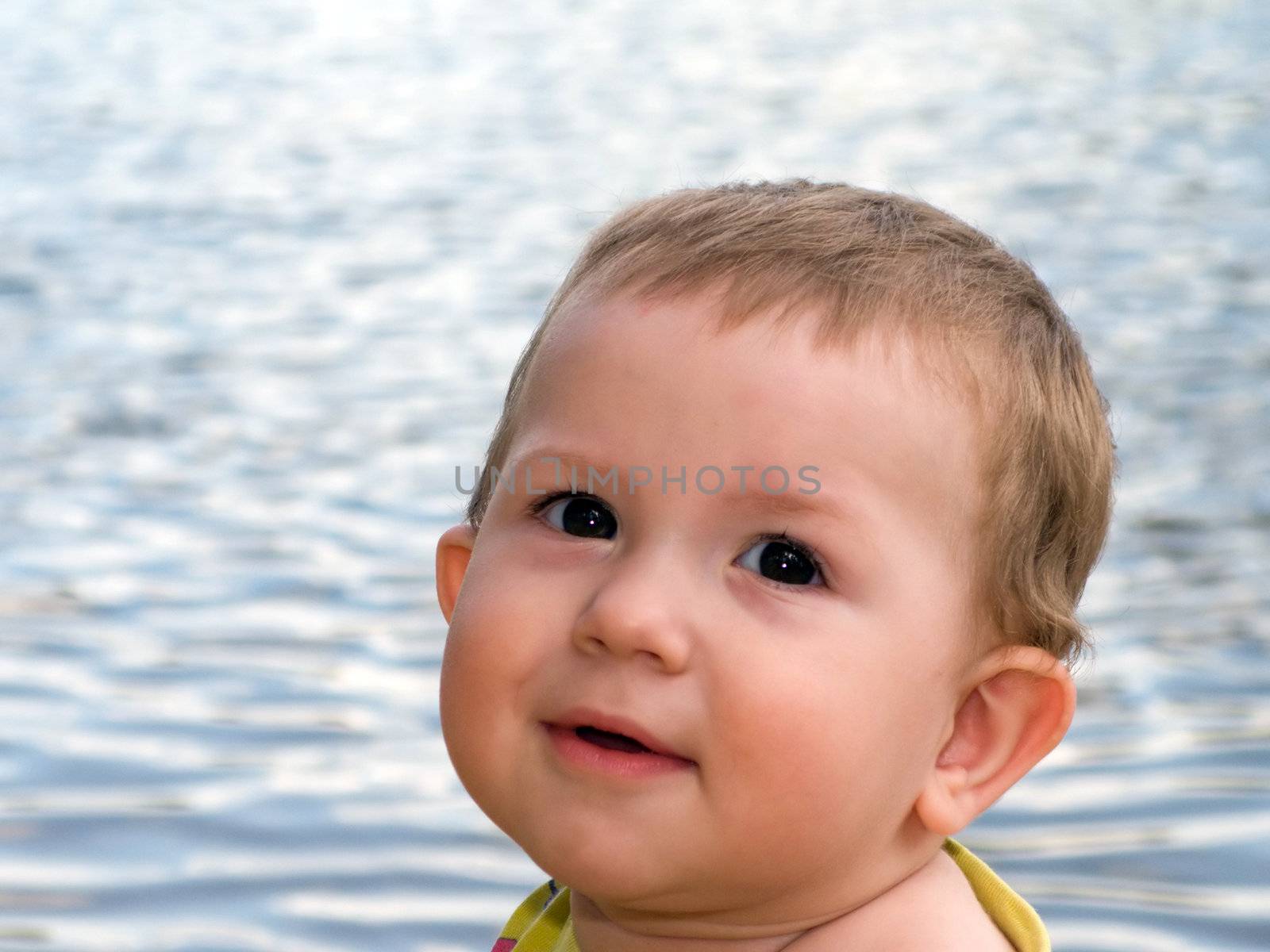 Little child smiling on water beach at summer