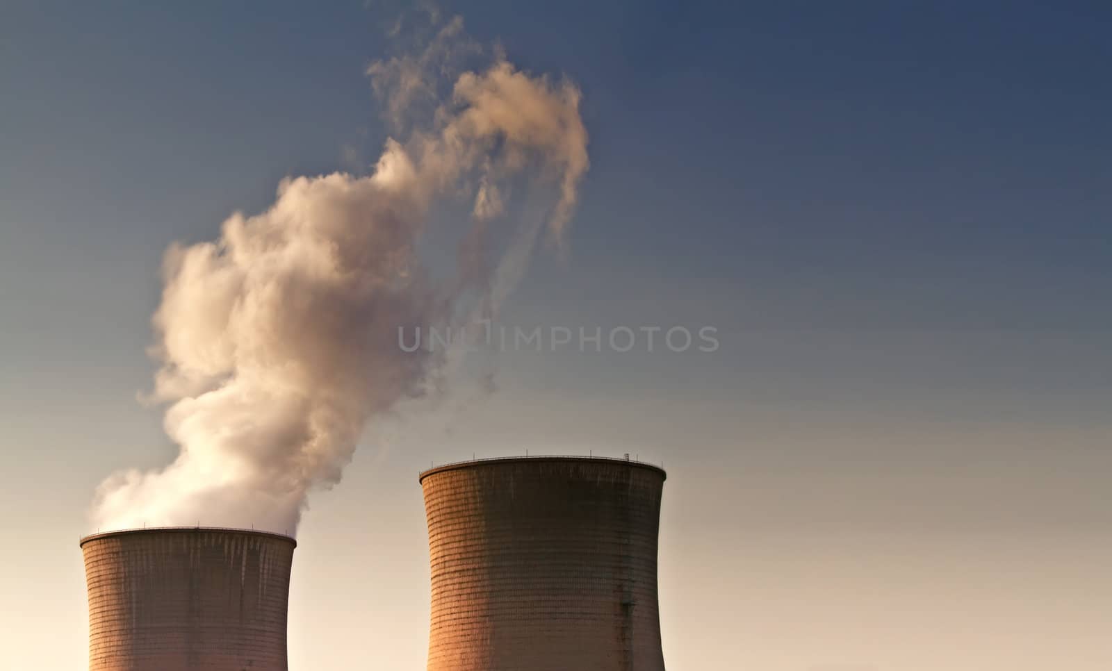 Landscape photo of giant power supply chimneys smoking in the sky
