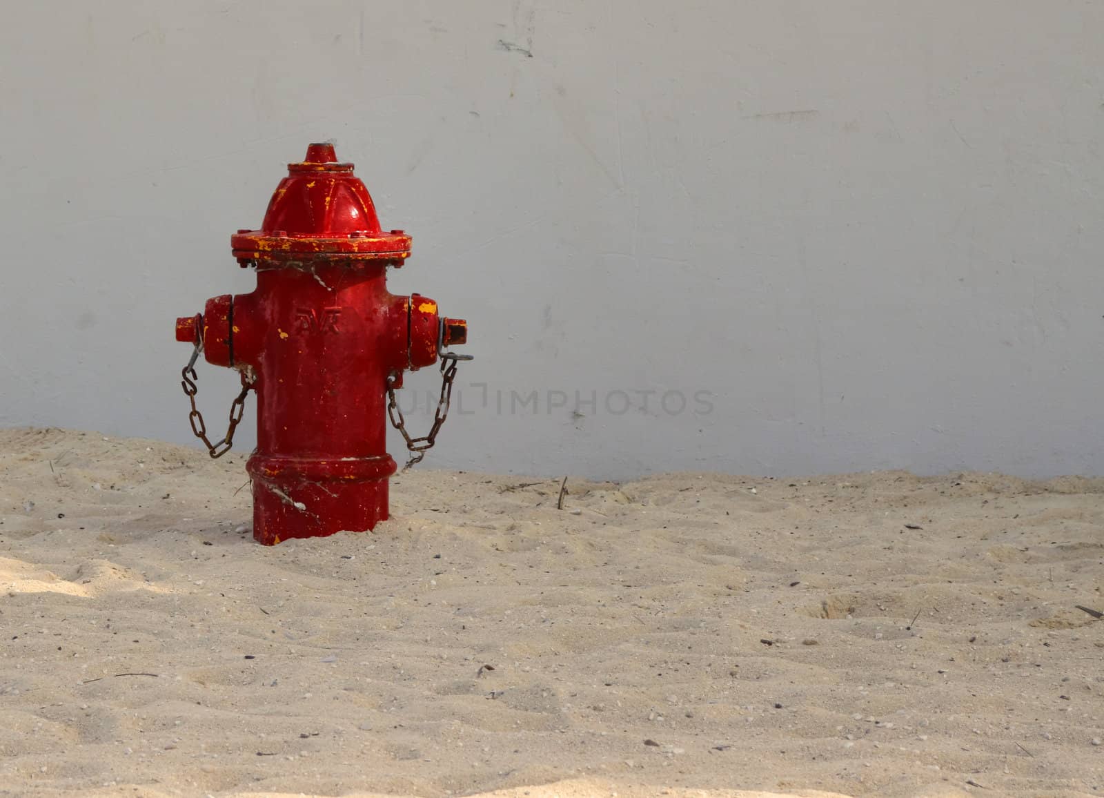 Left side view of red fire hydrant on a sandy beach