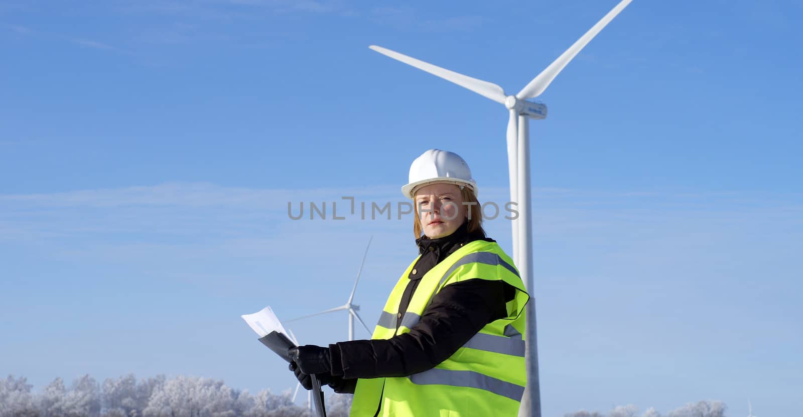 engineer or architect with white safety hat and wind turbines on by nostal6ie