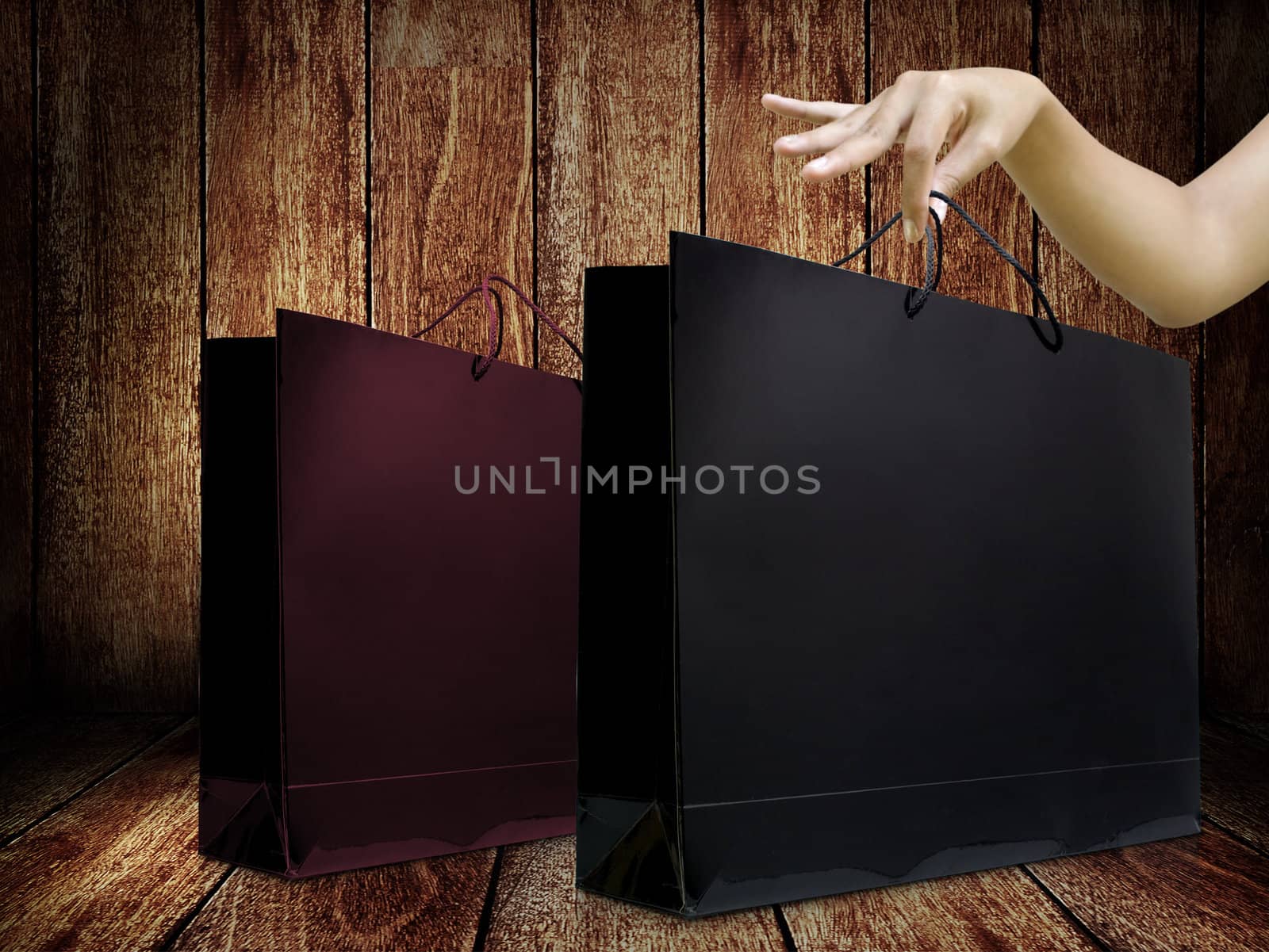 Glossy shopping bag in lady hand with wooden background by pixbox77