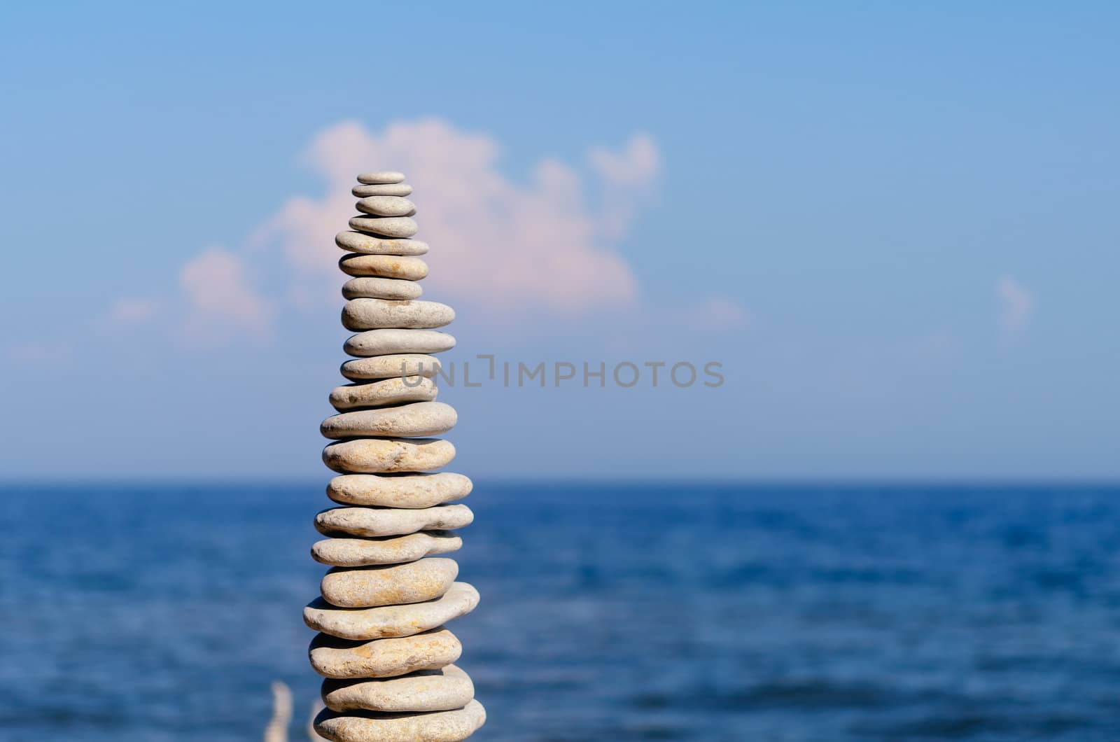 Balancing white pebbles each other on a sky background