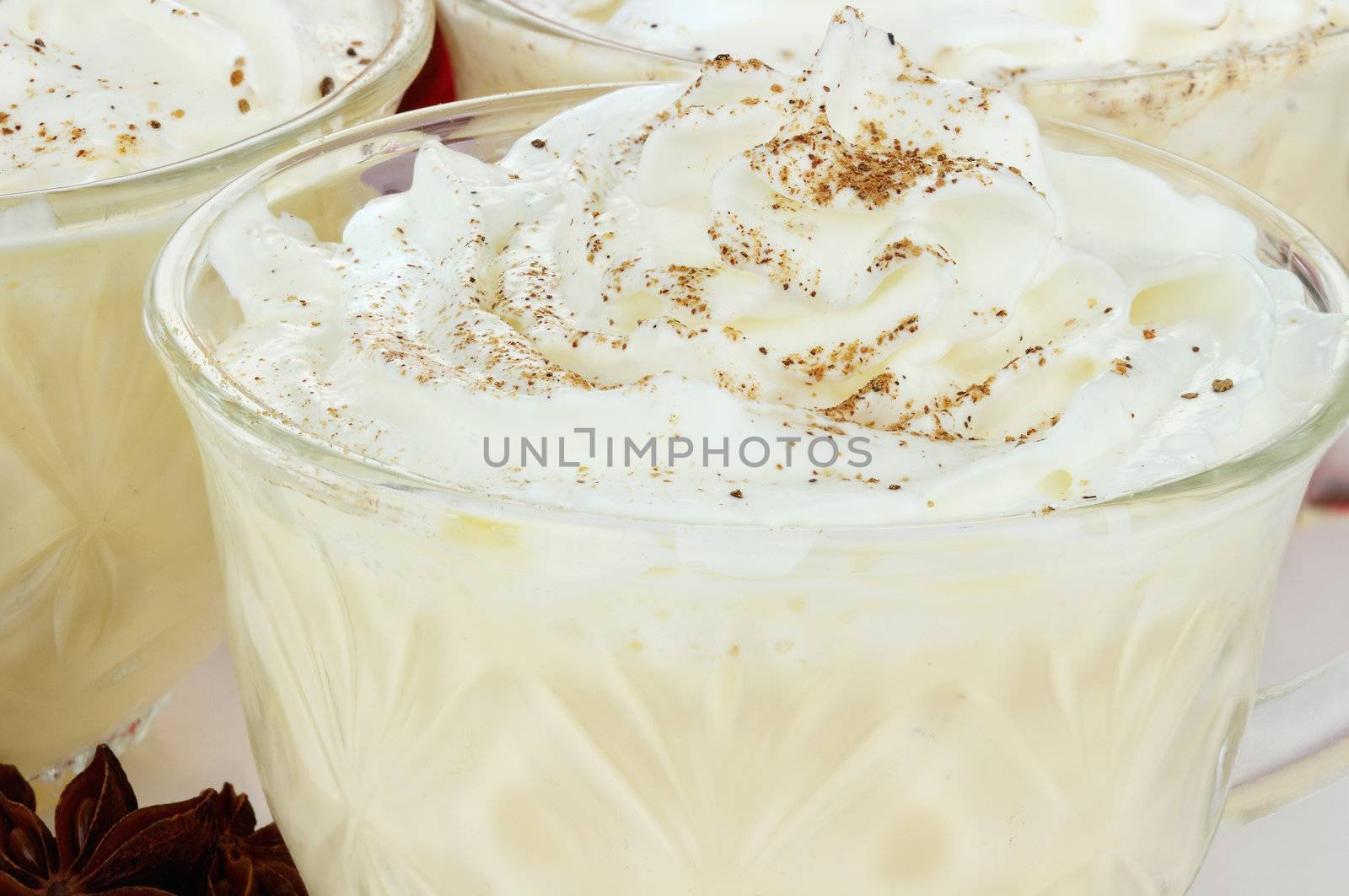 Eggnog with whipped cream and spices. Selective focus with some blur on lower portion of image.