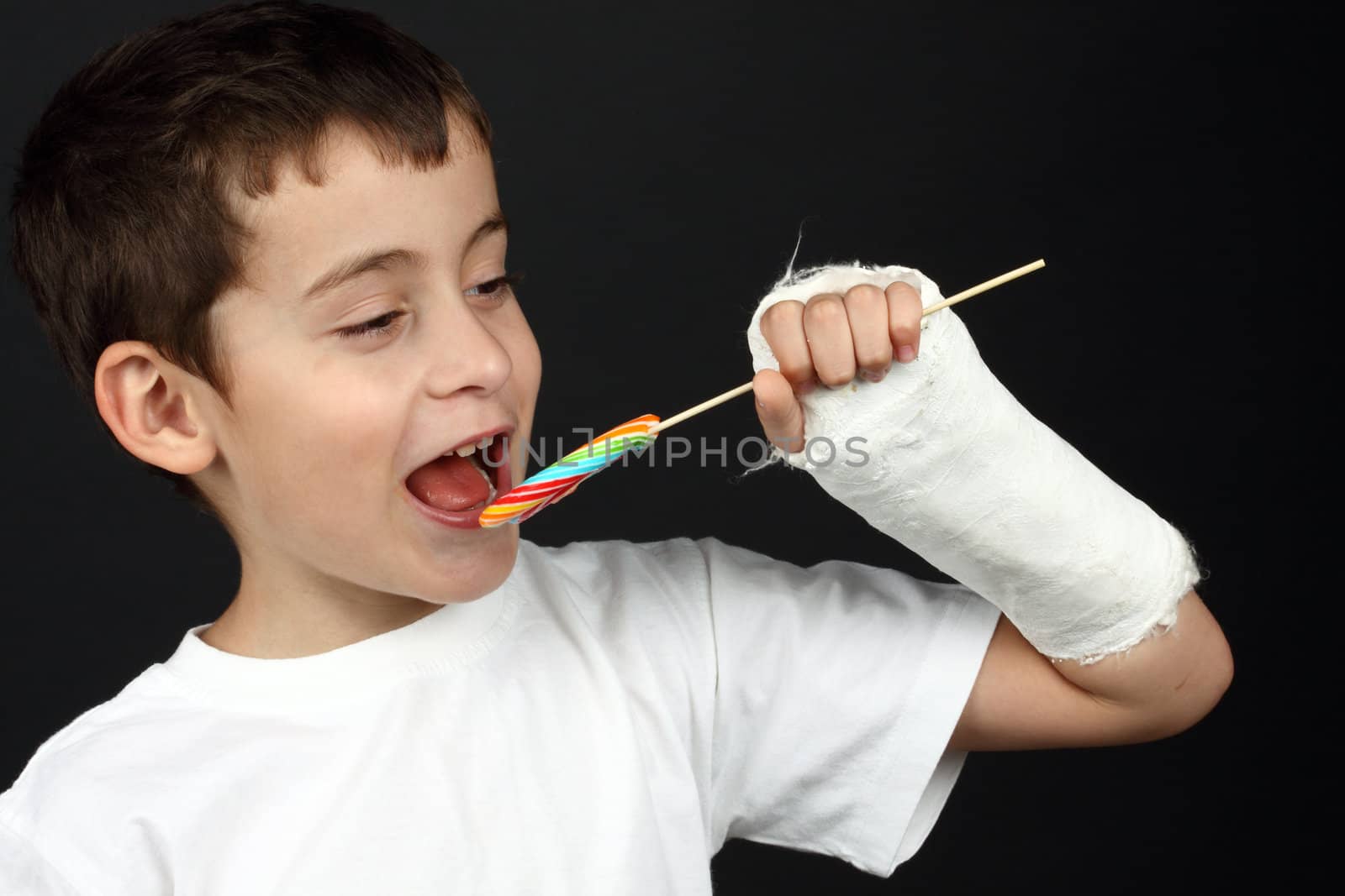 Boy with broken hand in cast, holding a lollipop 