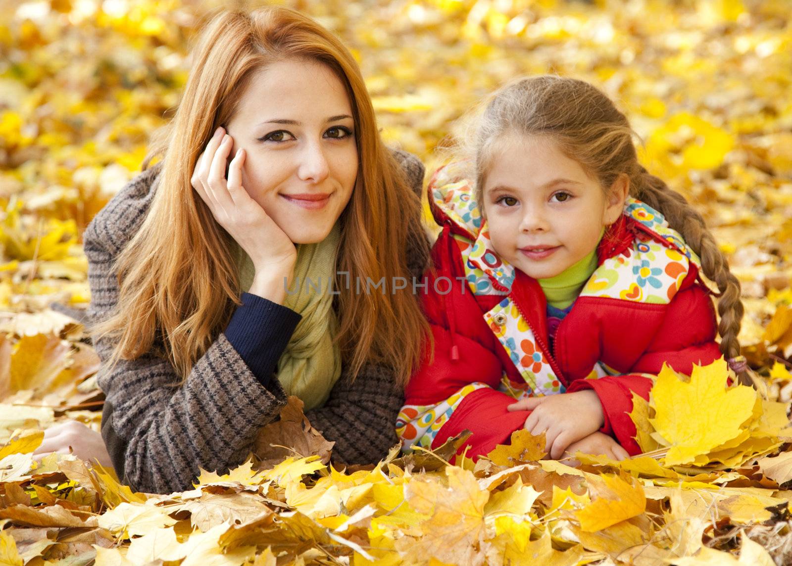 Mother and daughter in autumn yellow park by masson