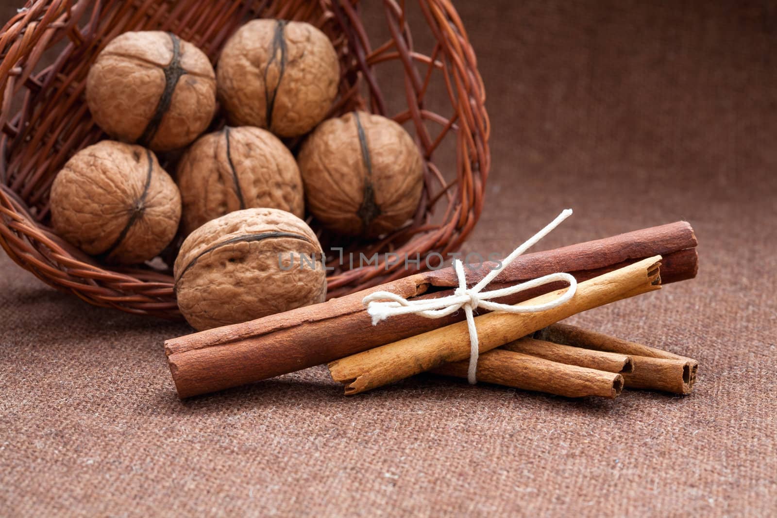 Walnuts in a wicker basket and cinnamon, burlap background