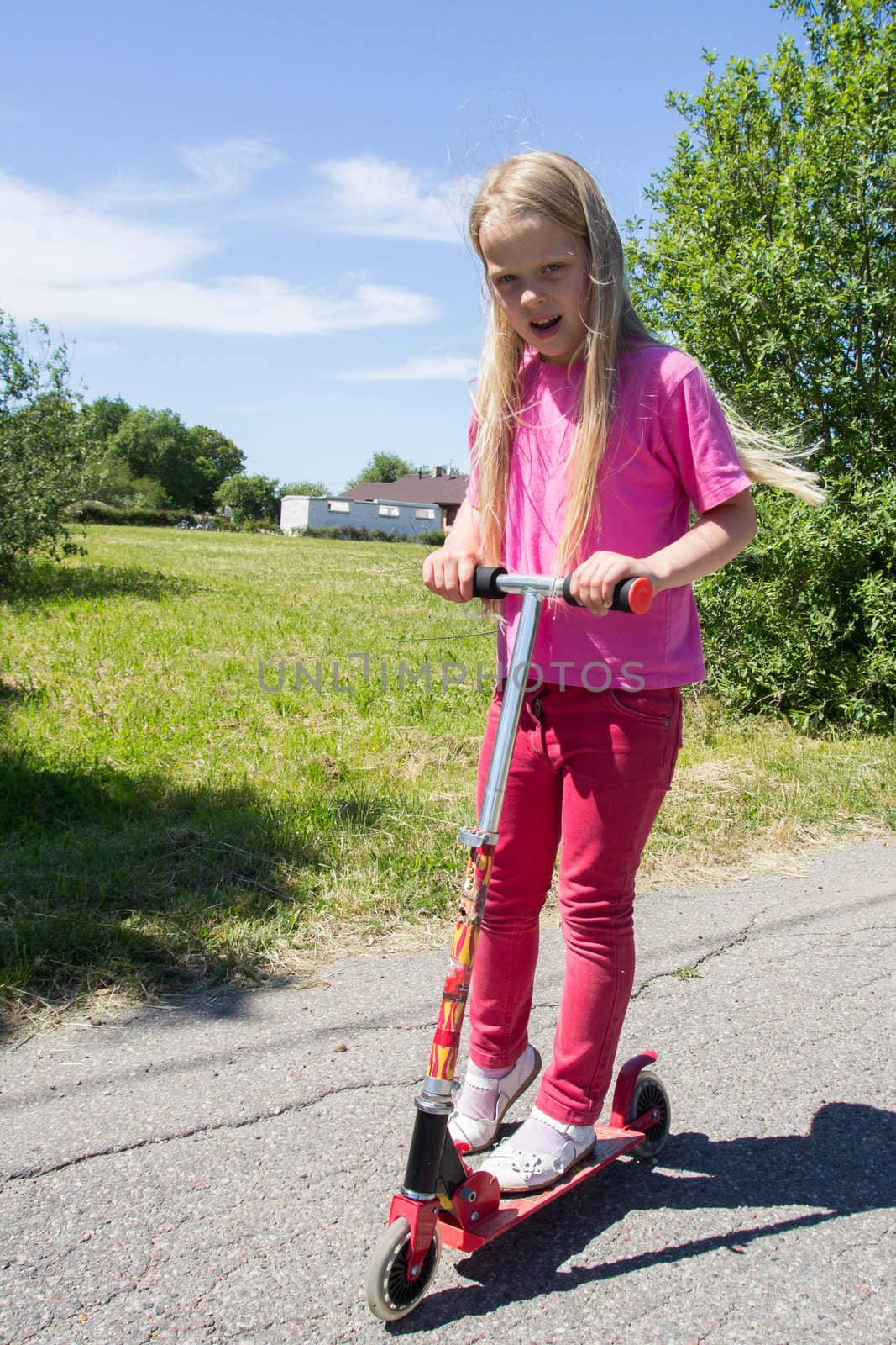 little girl rides a scooter on a rural road