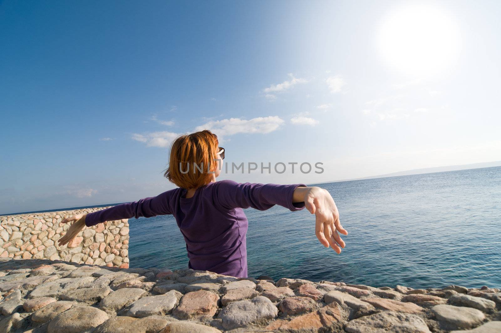 Happy young red woman with outstretched hands enjoying the sun