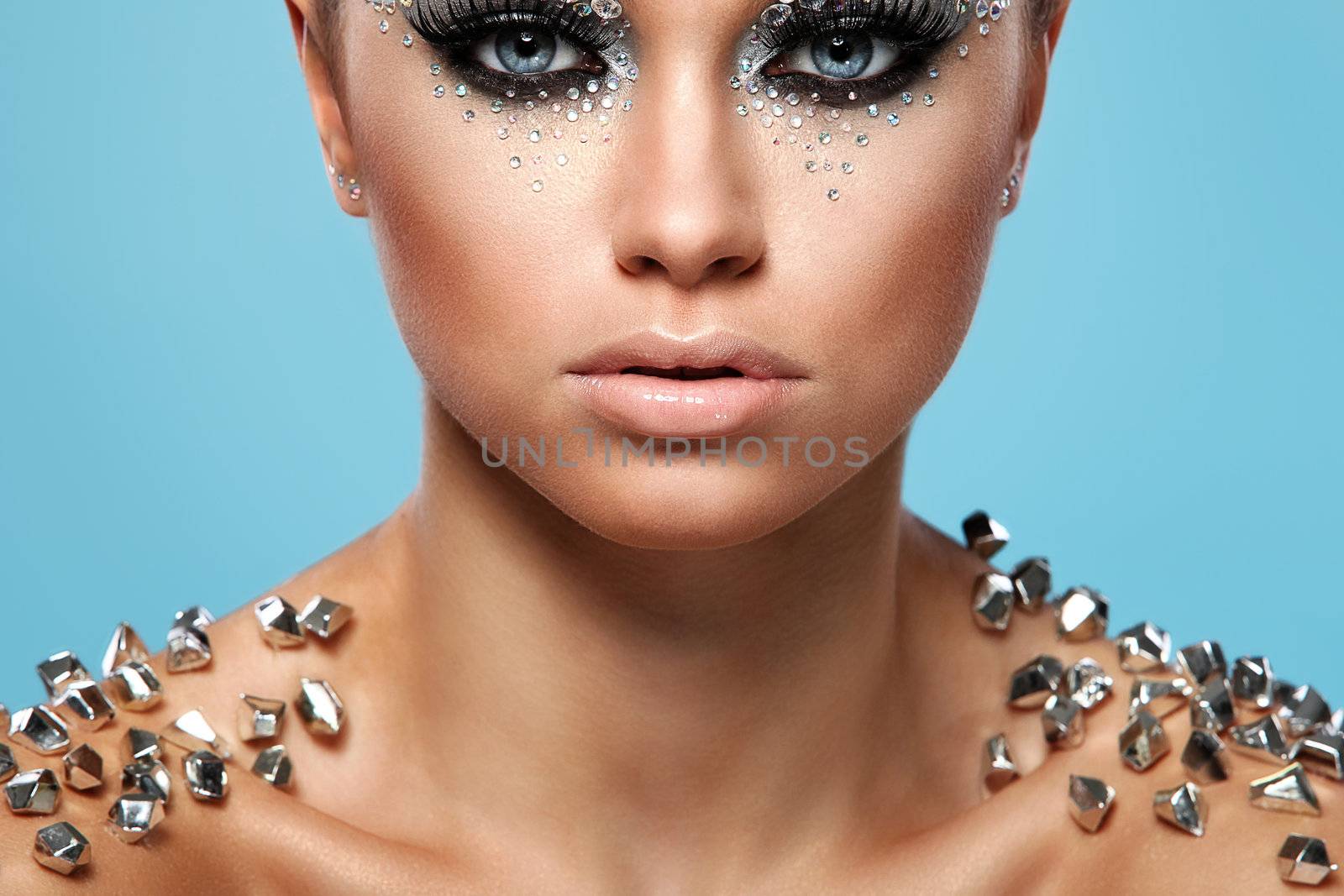 Portrait of woman with artistic make-up and rhinestones over background