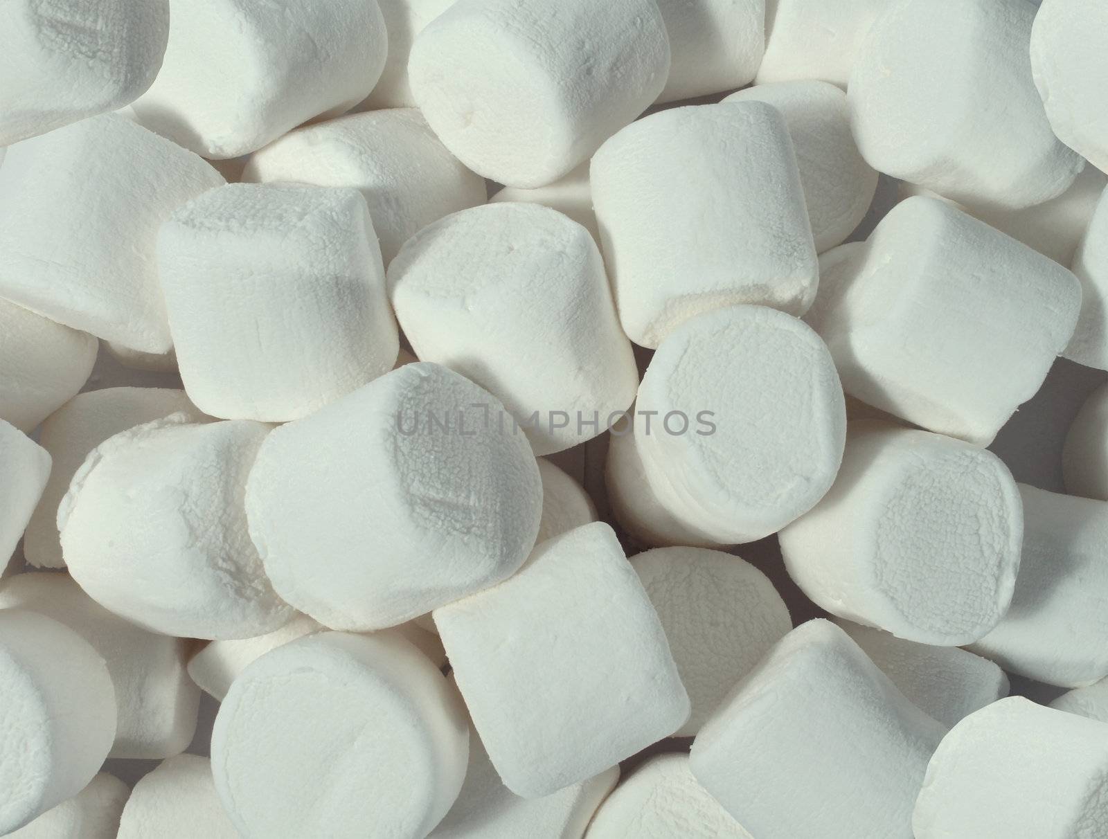 Marshmallows candy in a group as soft white confectionery store display representing a fun sweet treat for kids and a dessert snack for older children.