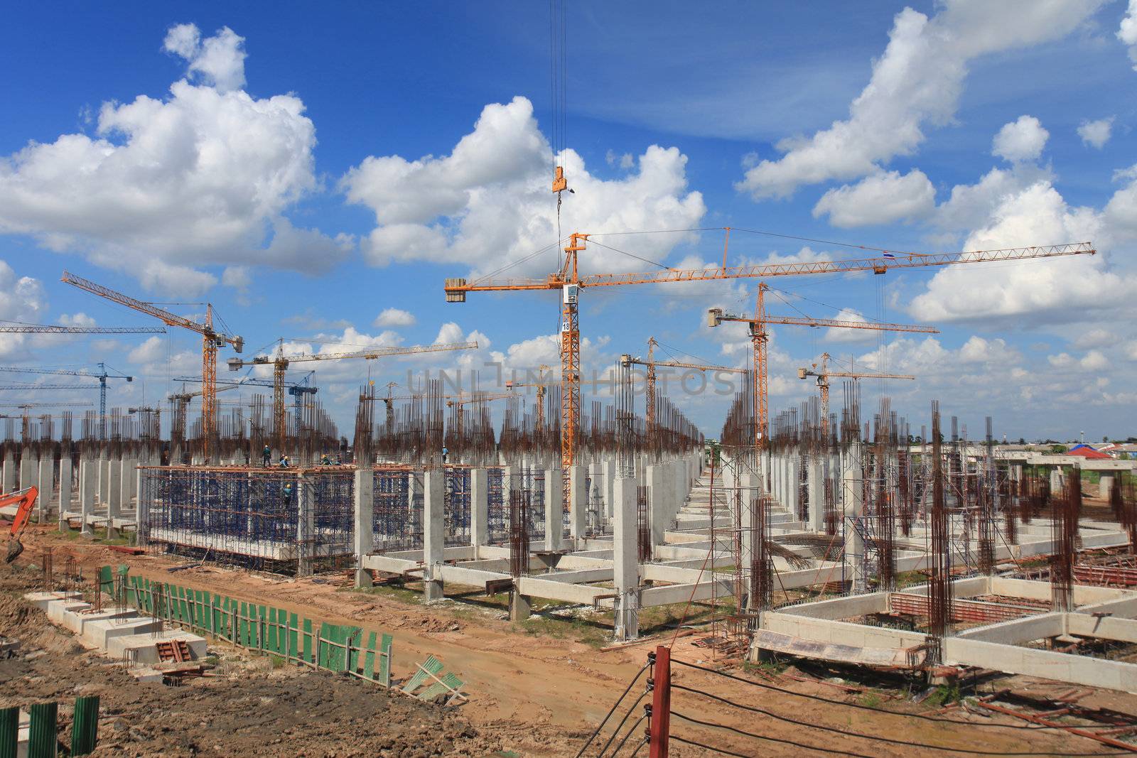 Large construction sites. Tower crane up to 22 with the hot sun. Beautiful sky with clouds.