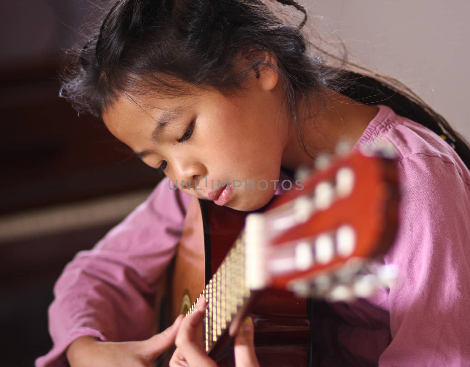 Cute girl playing guitar indoor with high concentration