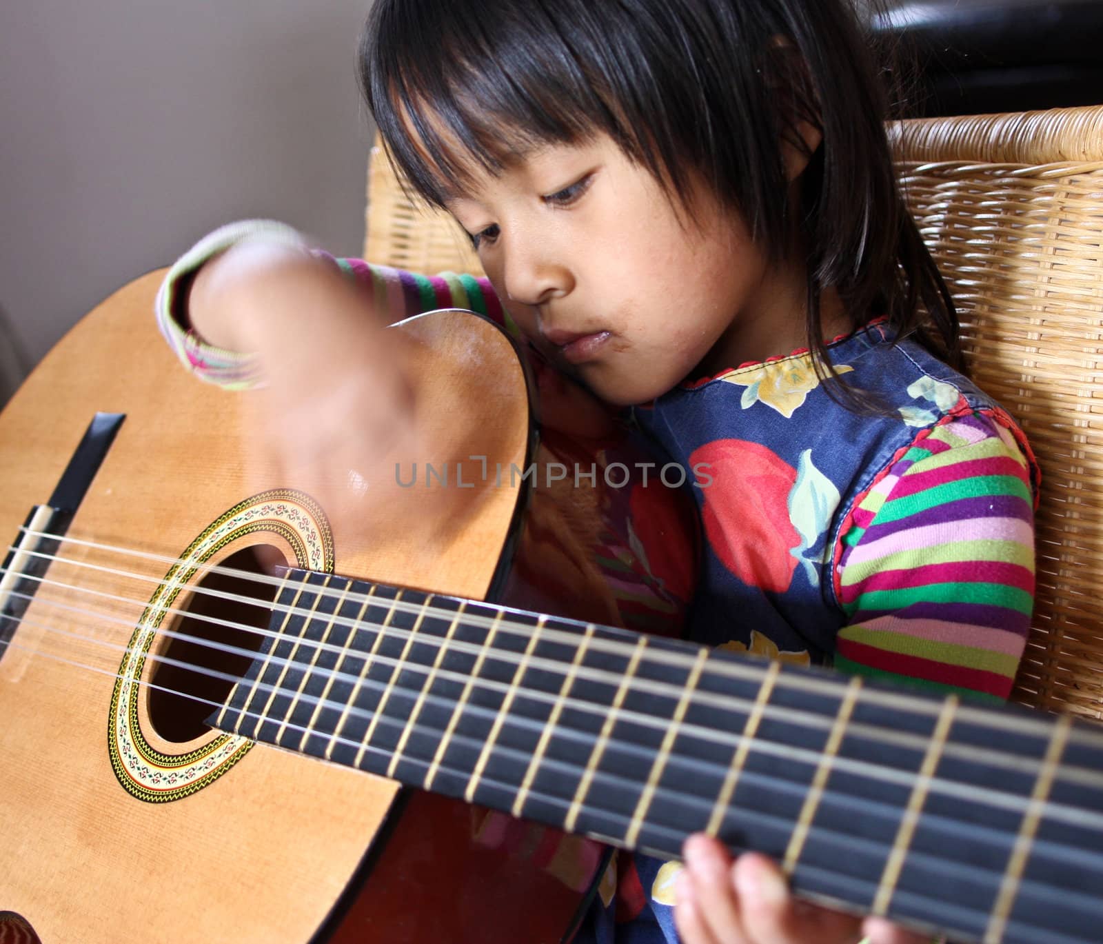 Cute girl playing guitar indoor with high concentration