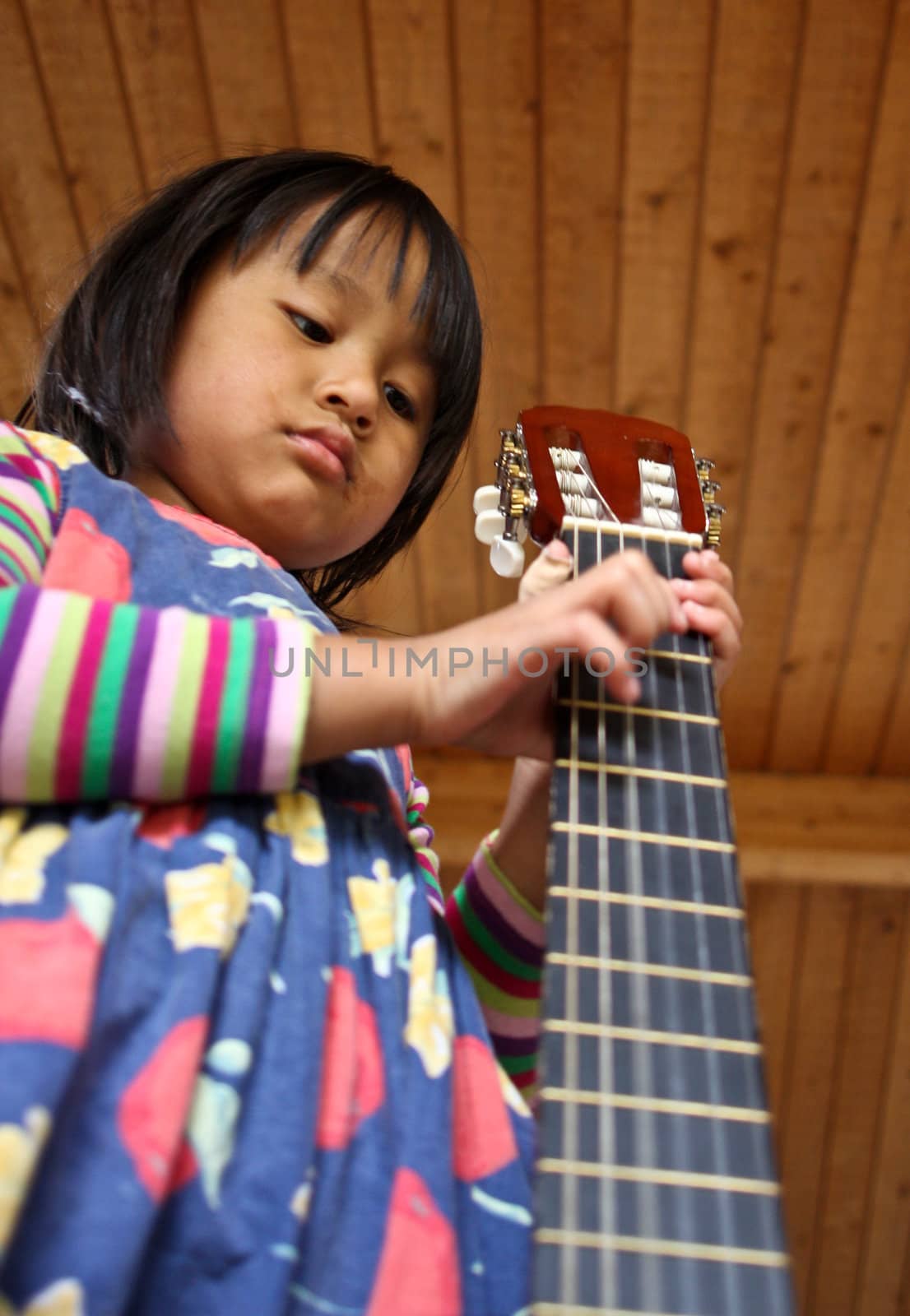 Cute girl playing guitar indoor with high concentration