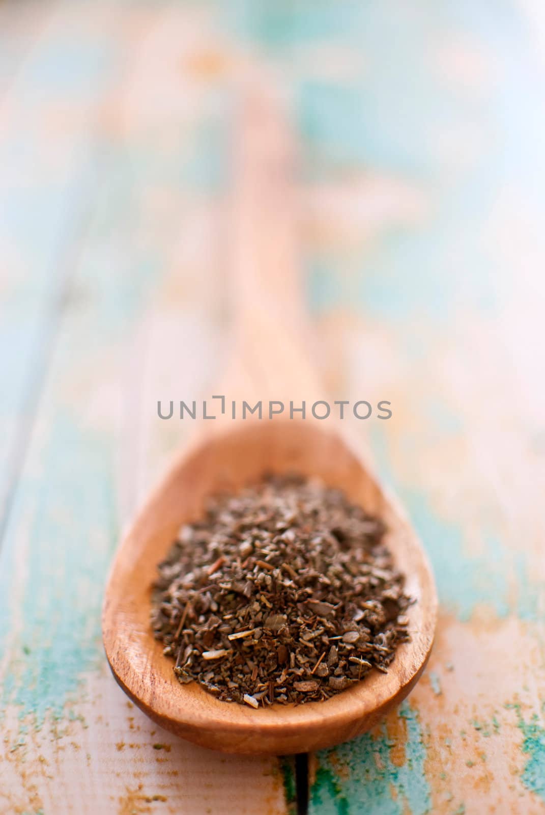 sage spice in wooden spoon over wood background - selective focus