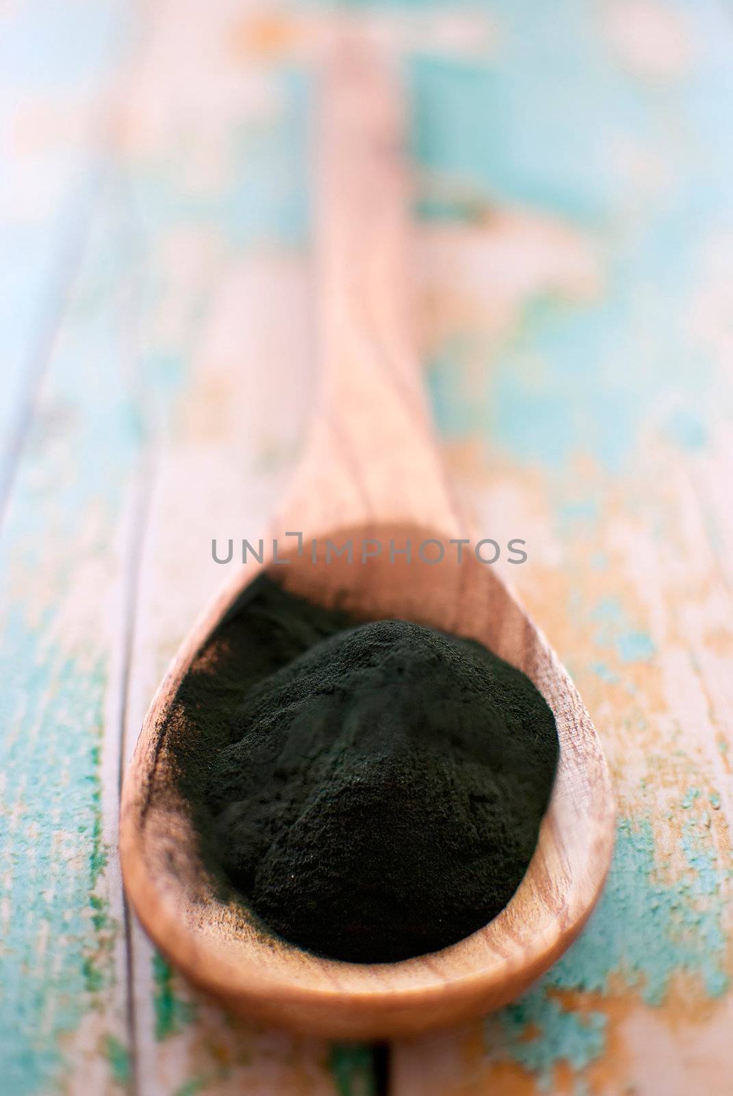 organic spirulina algae powder in wooden spoon