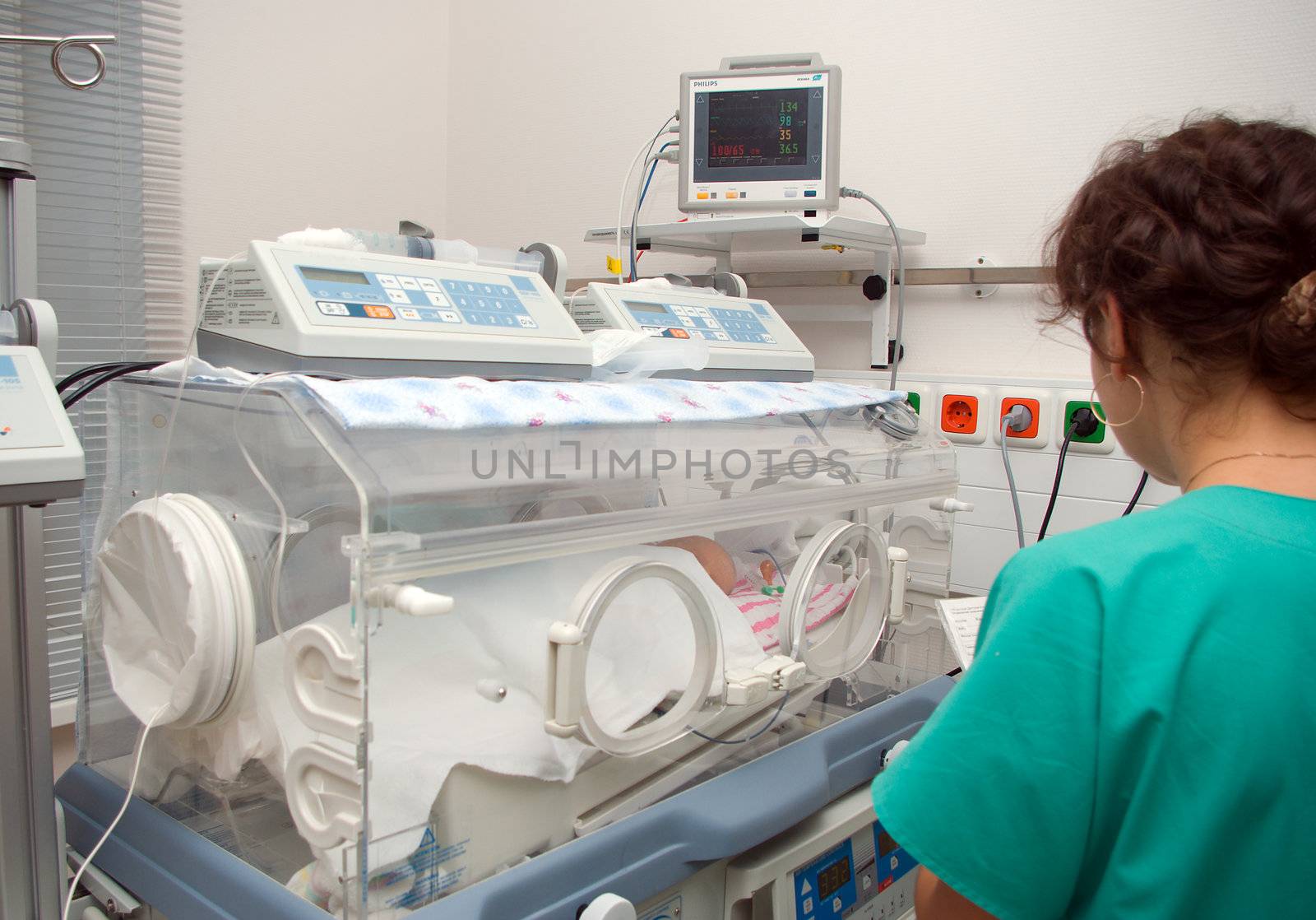 experienced physician and  newborn baby sleeping in an incubator in hospital