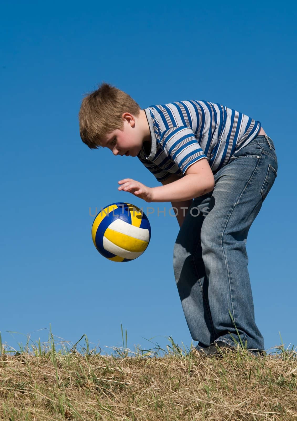 little boy with volleyball ball on a blue sky
