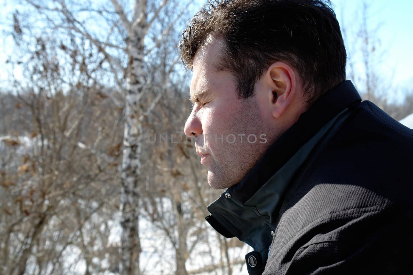Winter. The young man in a profile against birches.