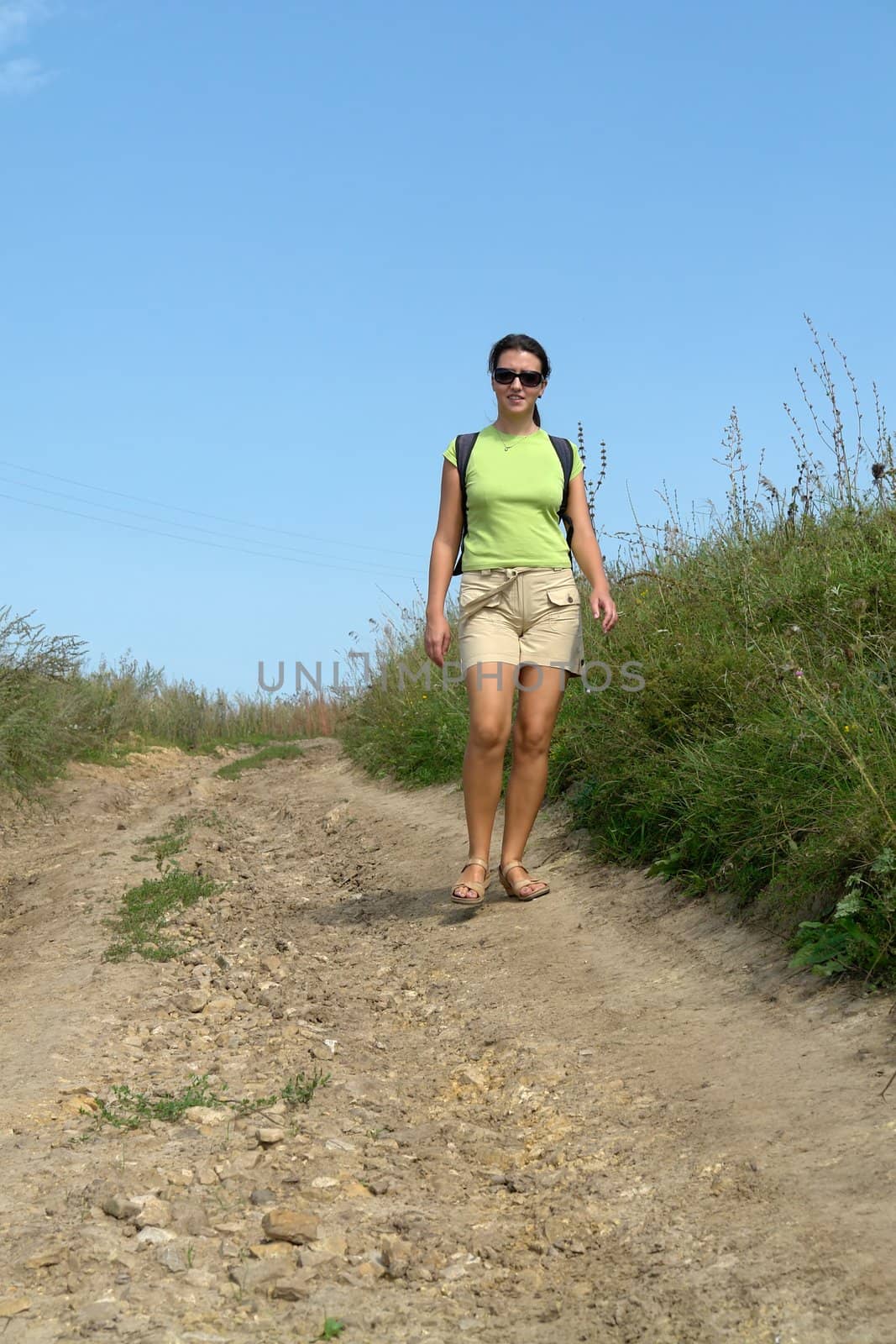 woman going on rural road against the sky