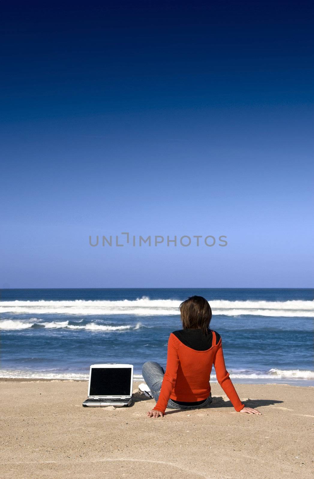 Woman working with a laptop on the beach