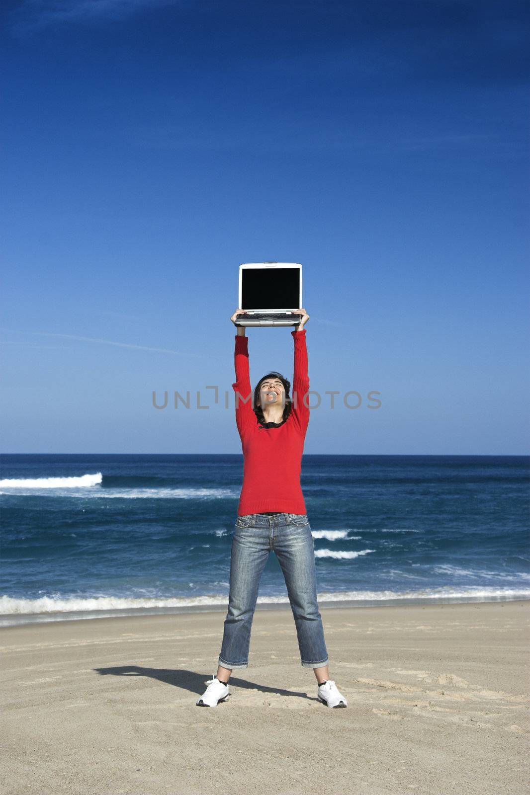 Woman on the beach holding a laptop