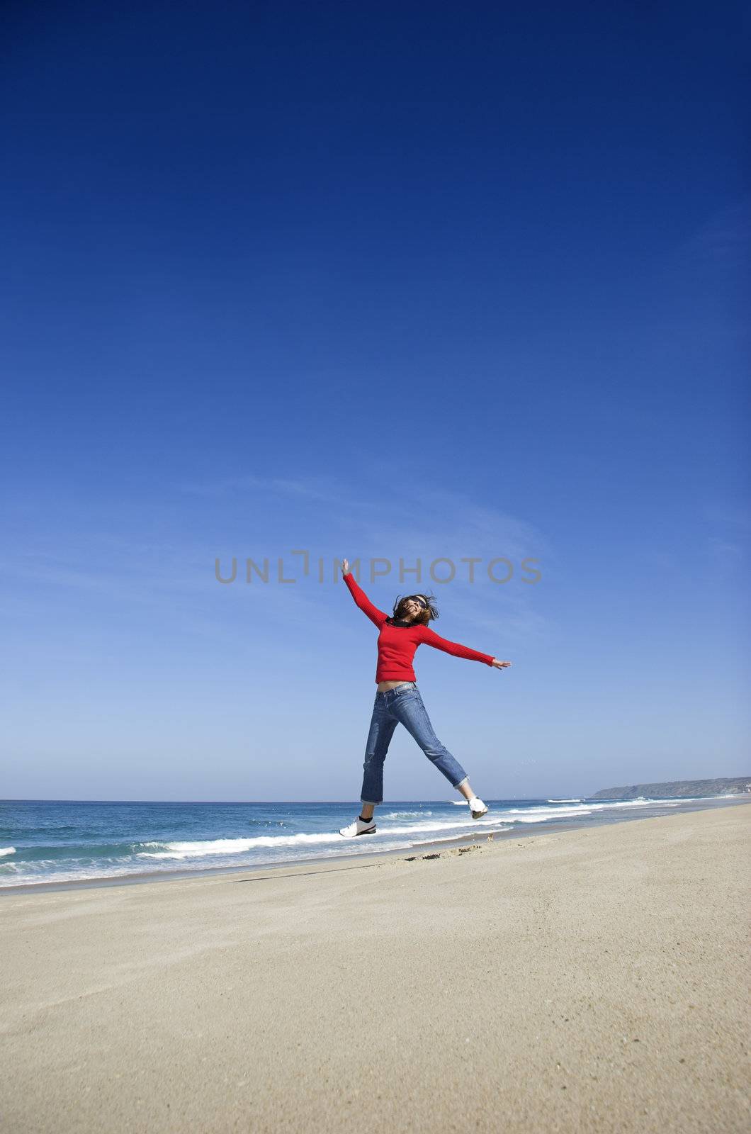 Young woman jumping on the beach and having fun