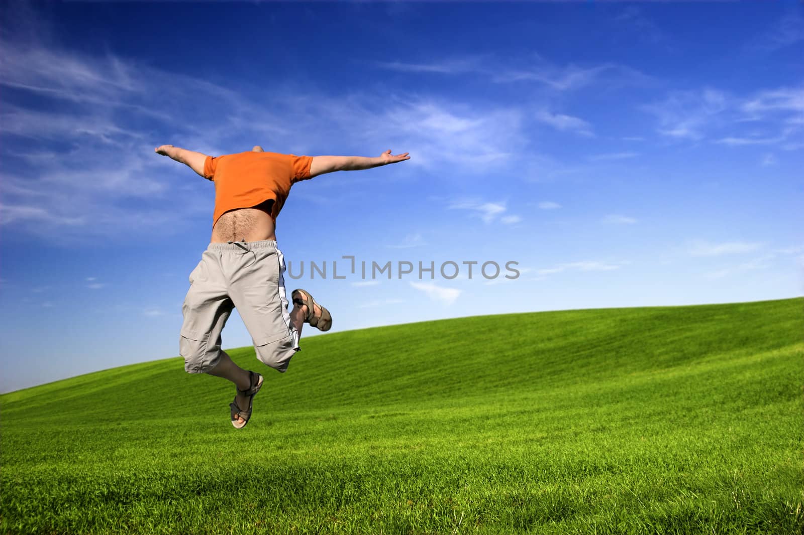 Man making a big jump on a beautiful green meadow