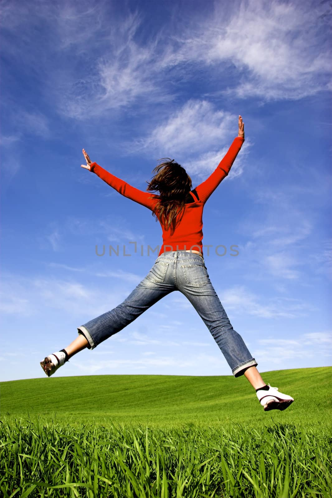 Woman making a big jump on a beautiful green meadow