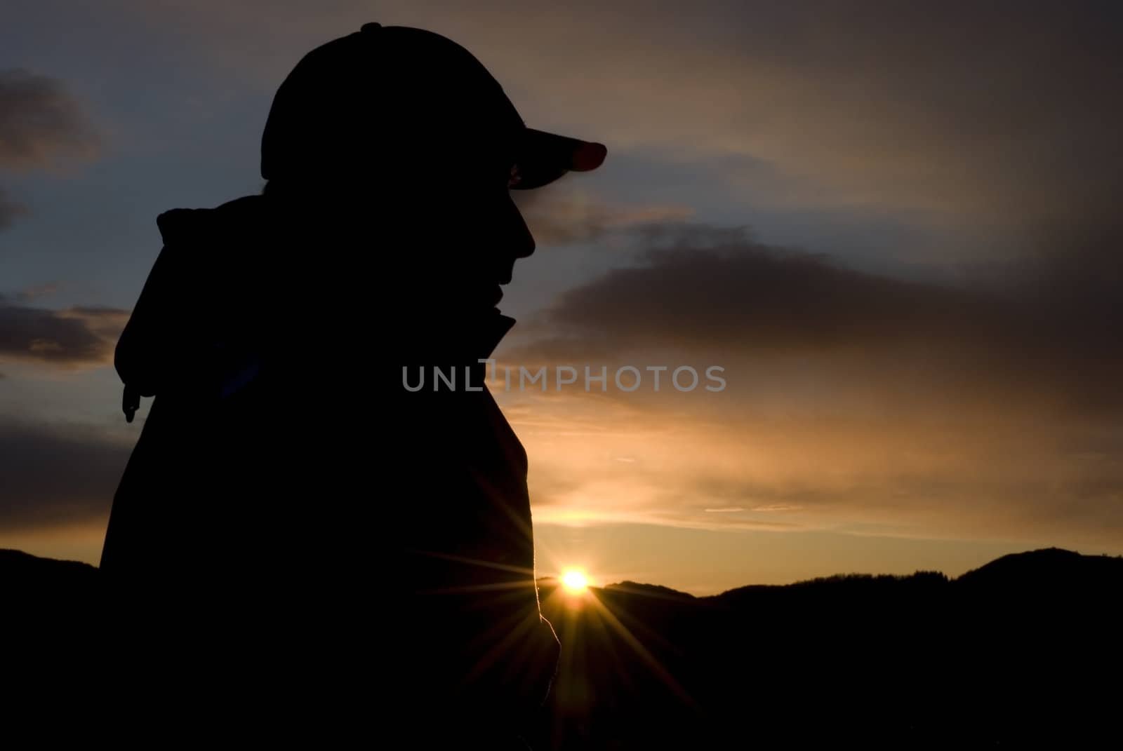 Male person sitting in the mountain under sunset!