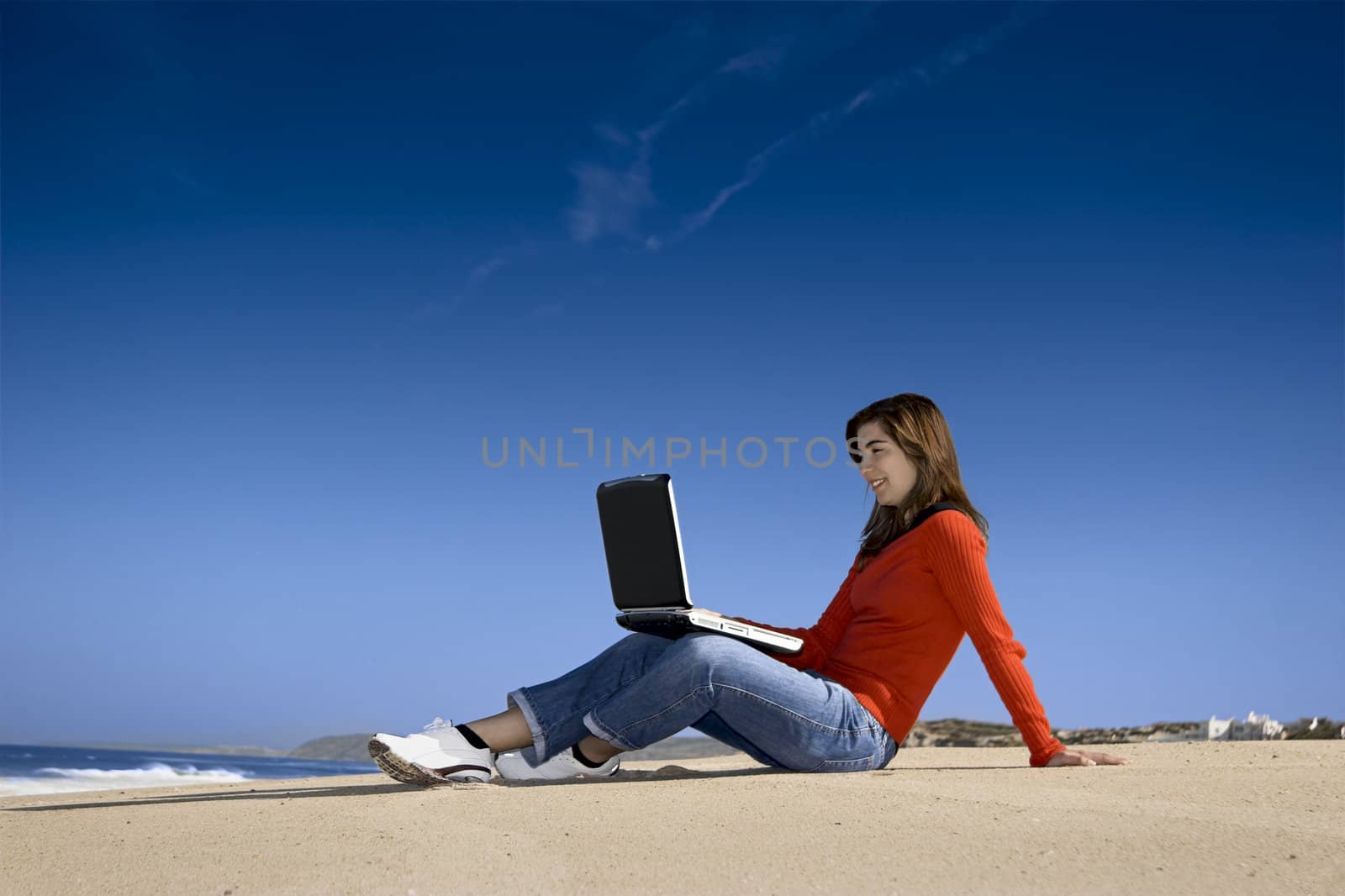 Woman working with a laptop on the beach