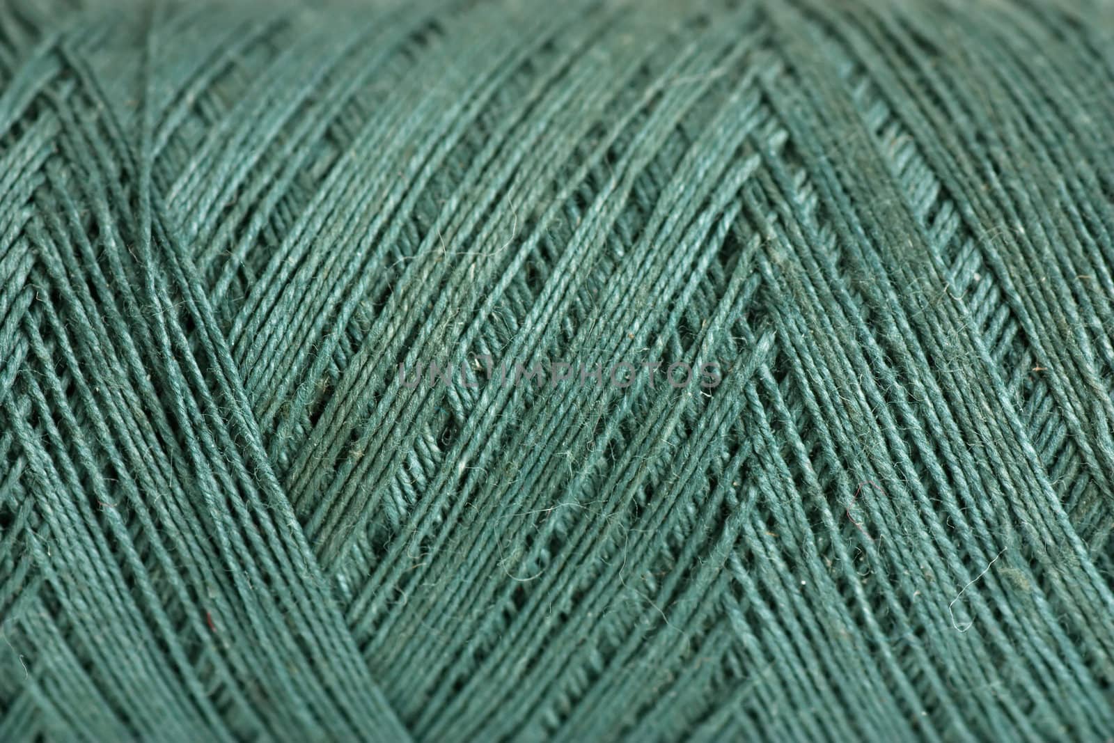 Macro view of reel of green thread. Green background