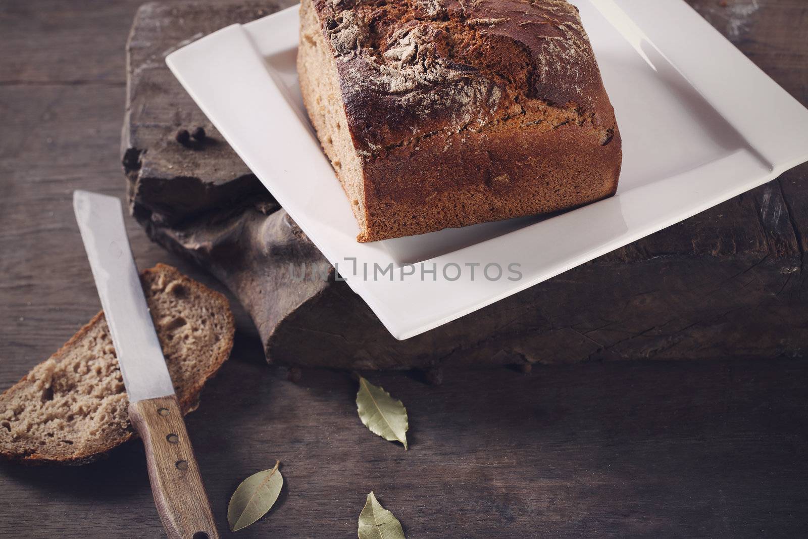 Knife with brown bread on a plate by robert_przybysz