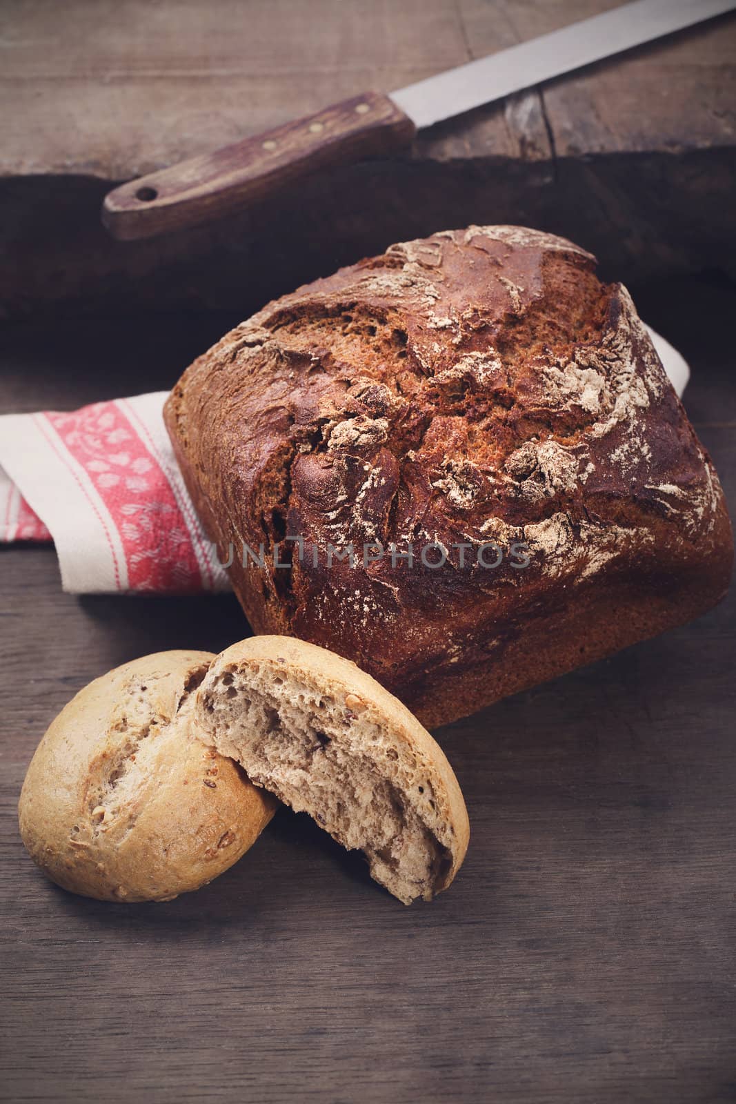 Black bread with a knife on a wooden table by robert_przybysz