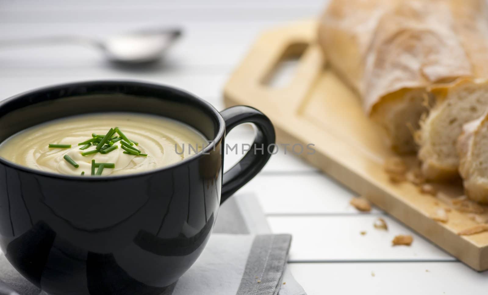 Mug full of fresh homemade potato soup garnished with cream and chives