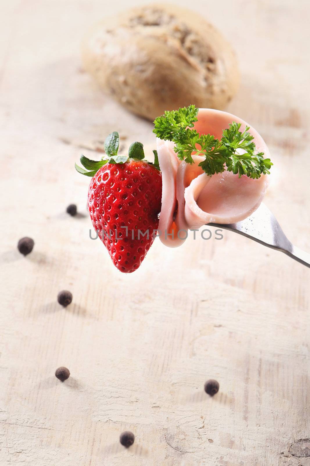 Strawberries and chop meat on a fork