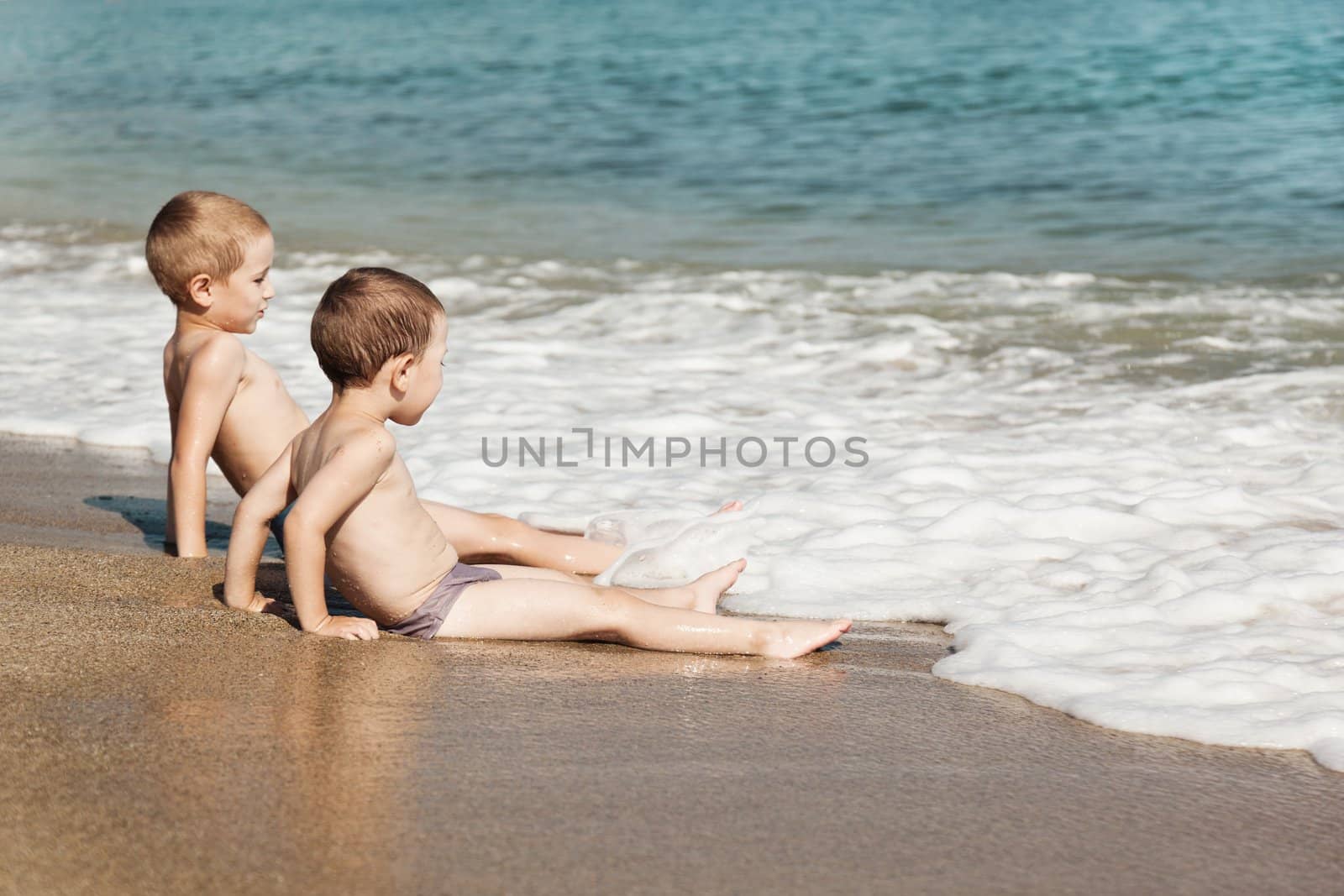 Summer vacations - two little child boy brothers playing on blue sea sand beach