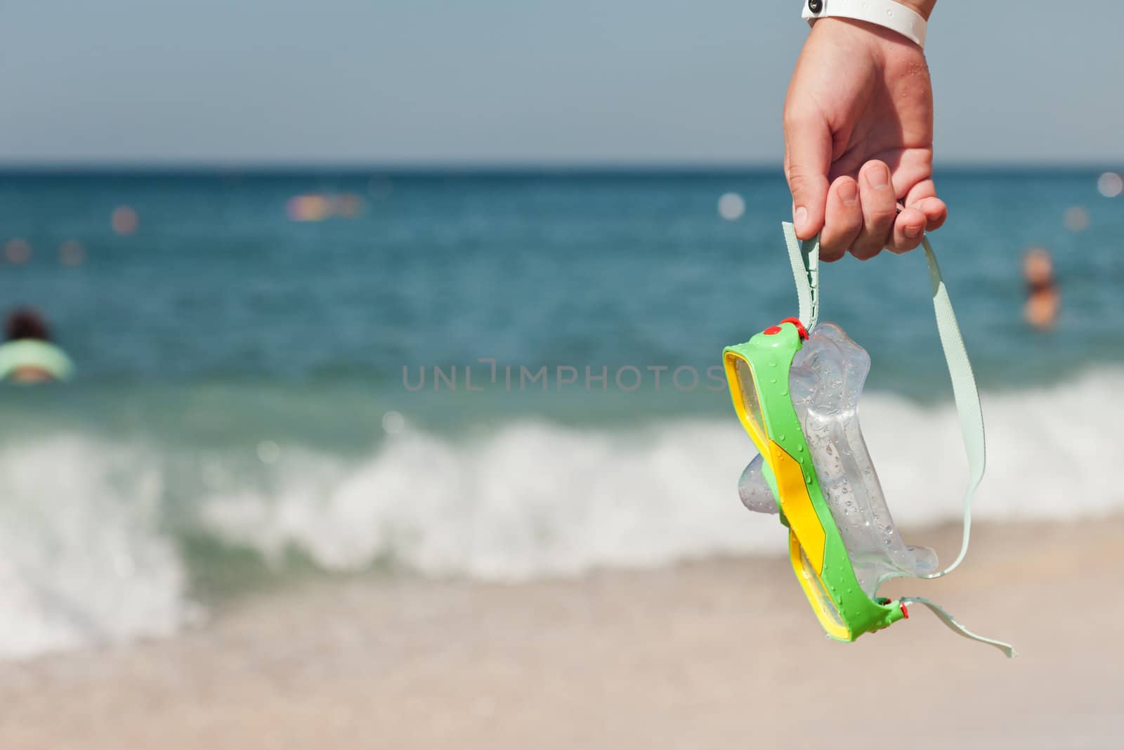 Summer vacations - woman hand holding underwater scuba diving goggles or mask on blue sea sand beach