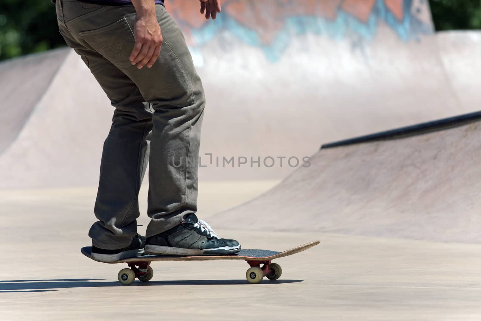 Action shot of a skateboarder skating at the skate park with concrete ramps.
