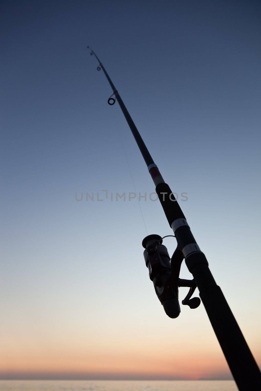 Fisherman sport hobby fishing rod or spinning reel on sea beach sunset
