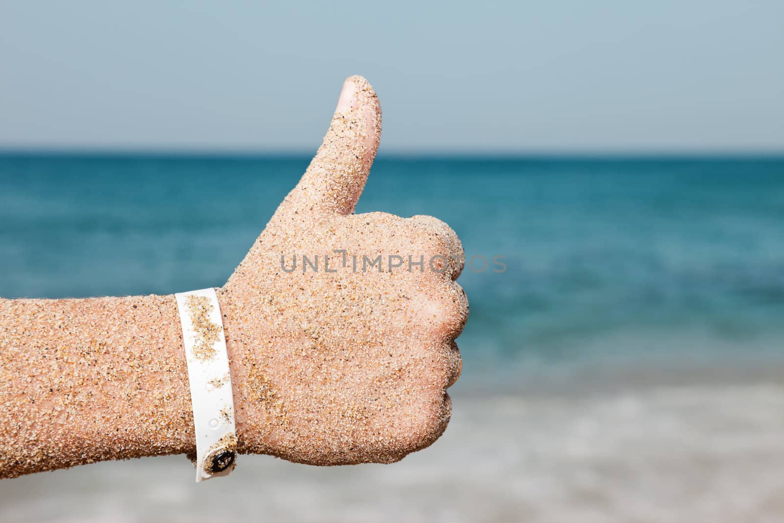 Summer vacations - woman hand gesturing thumb up success sign on sea sand beach