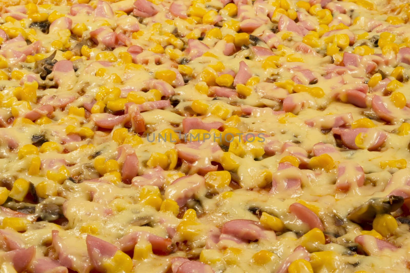 Large pizza closeup with cheese, sausage, corn and mushrooms, side view.