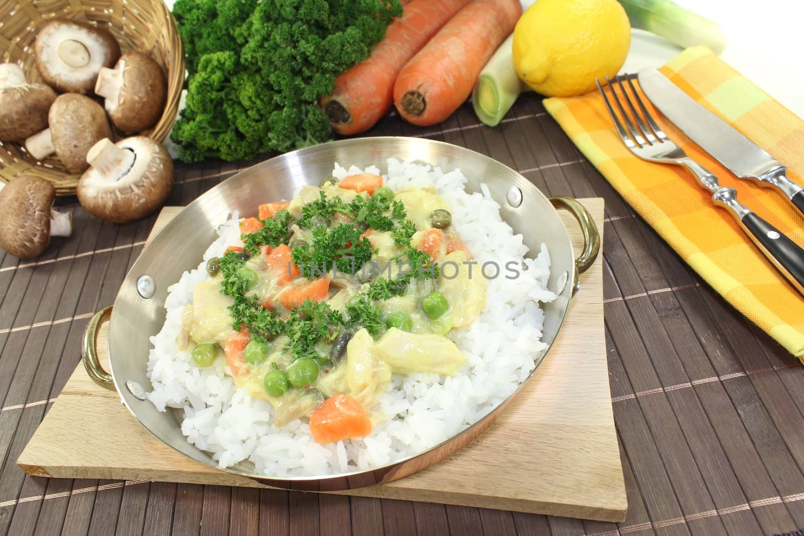 chicken frikassee with rice, vegetables and parsley in a pan