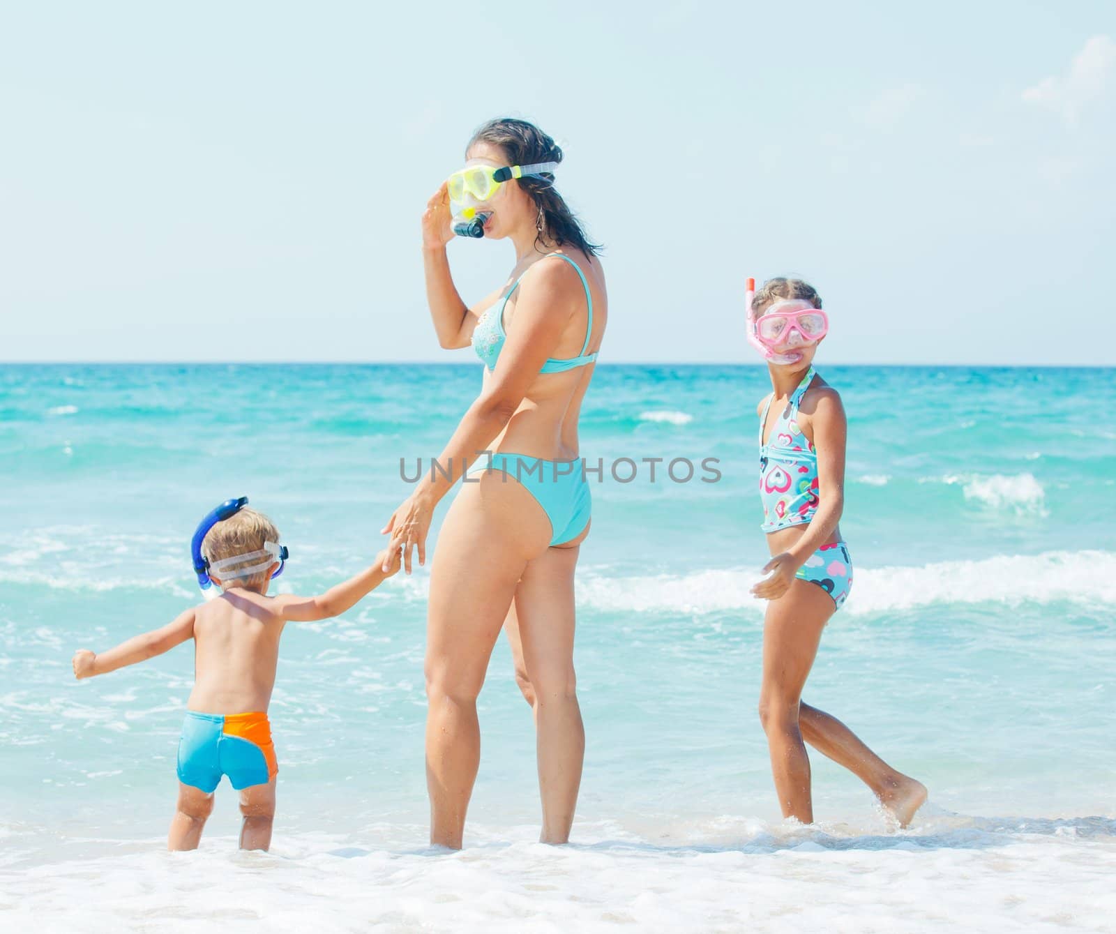 Happy young mother with her child with snorkeling equipment on sandy tropical beach