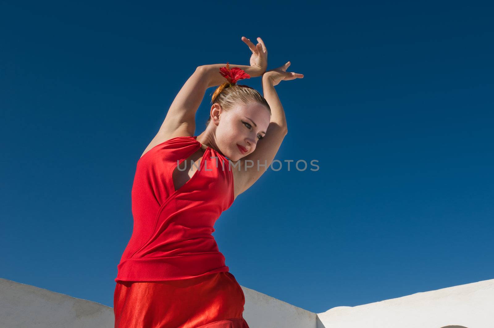 Attractive flamenco dancer wearing traditional red dress with flower in her hair