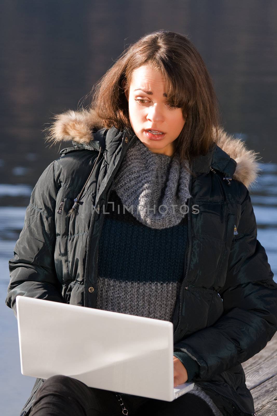 Woman sits on the lake and surf the internet with laptop